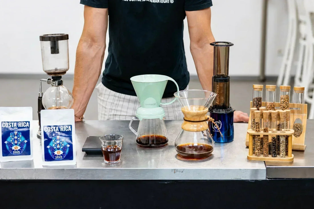 A set of specialty coffee brewing methods on a table – V60, AeroPress, and moka pot next to bags of JAVA Coffee