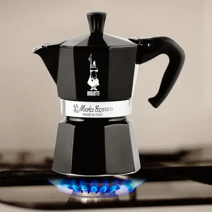 Czarna kawiarka Bialetti Moka Express podgrzewana na kuchence gazowej – klasyczny model w eleganckim wydaniu, idealny do domowego parzenia espresso.