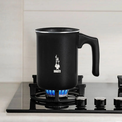Podgrzewanie mleka w czarnym ręcznym spieniaczu Bialetti Tuttocrema na kuchence gazowej – idealny do przygotowania cappuccino i latte