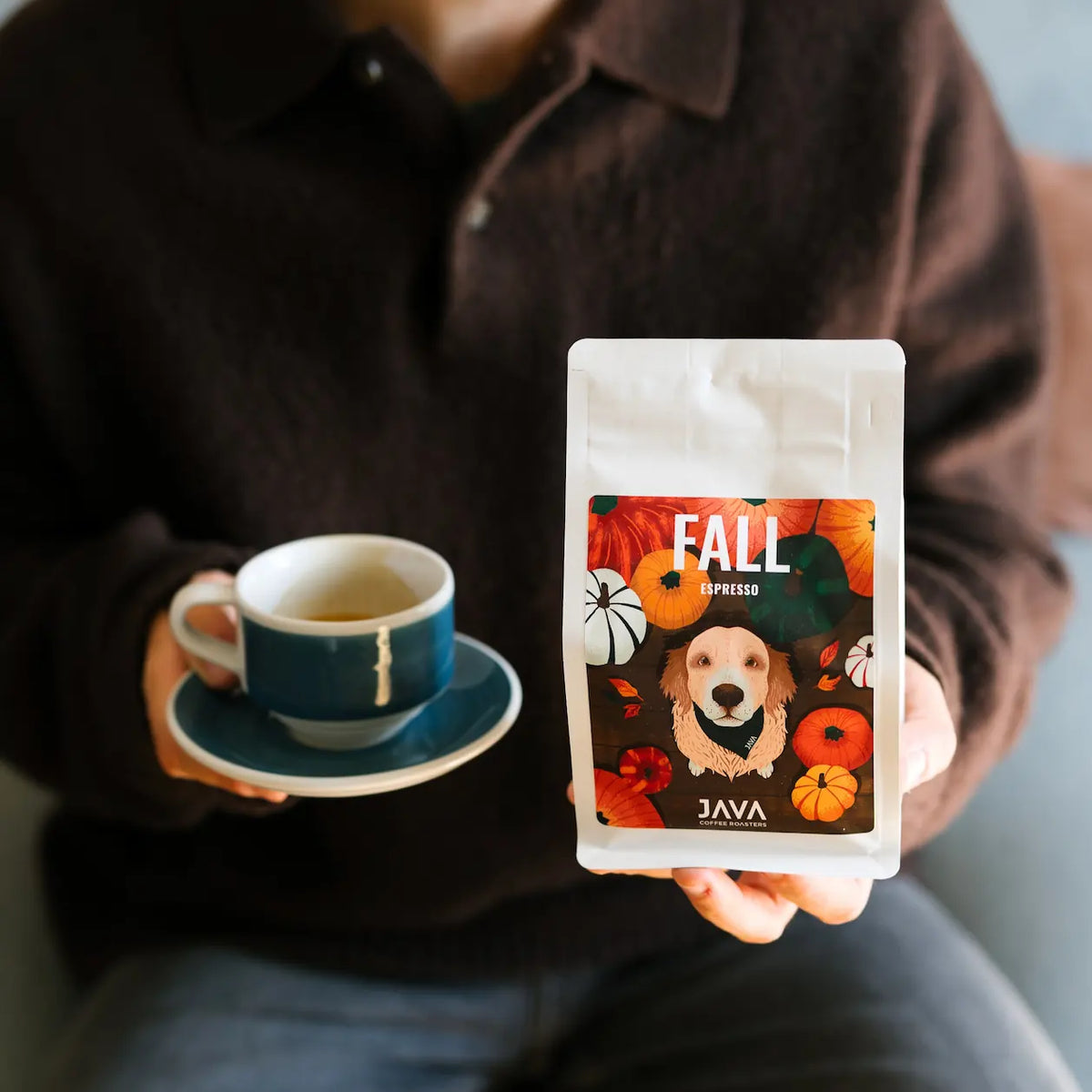Osoba trzymająca opakowanie sezonowej kawy specialty Ethiopia Aricha Fall Espresso JAVA Coffee Roasters oraz filiżankę espresso.