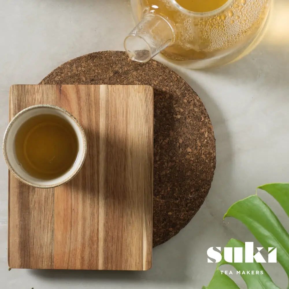 Herbata ziołowa Lemongrass & Ginger SUKI Tea – filiżanka zaparzonej herbaty z imbirem i trawą cytrynową na drewnianej desce, widok z góry