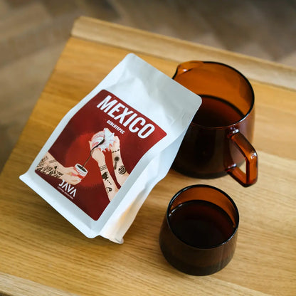 Kawa Mexico Ozolotepec od JAVA Coffee Roasters obok szklanego serwera i filiżanki na drewnianym stole