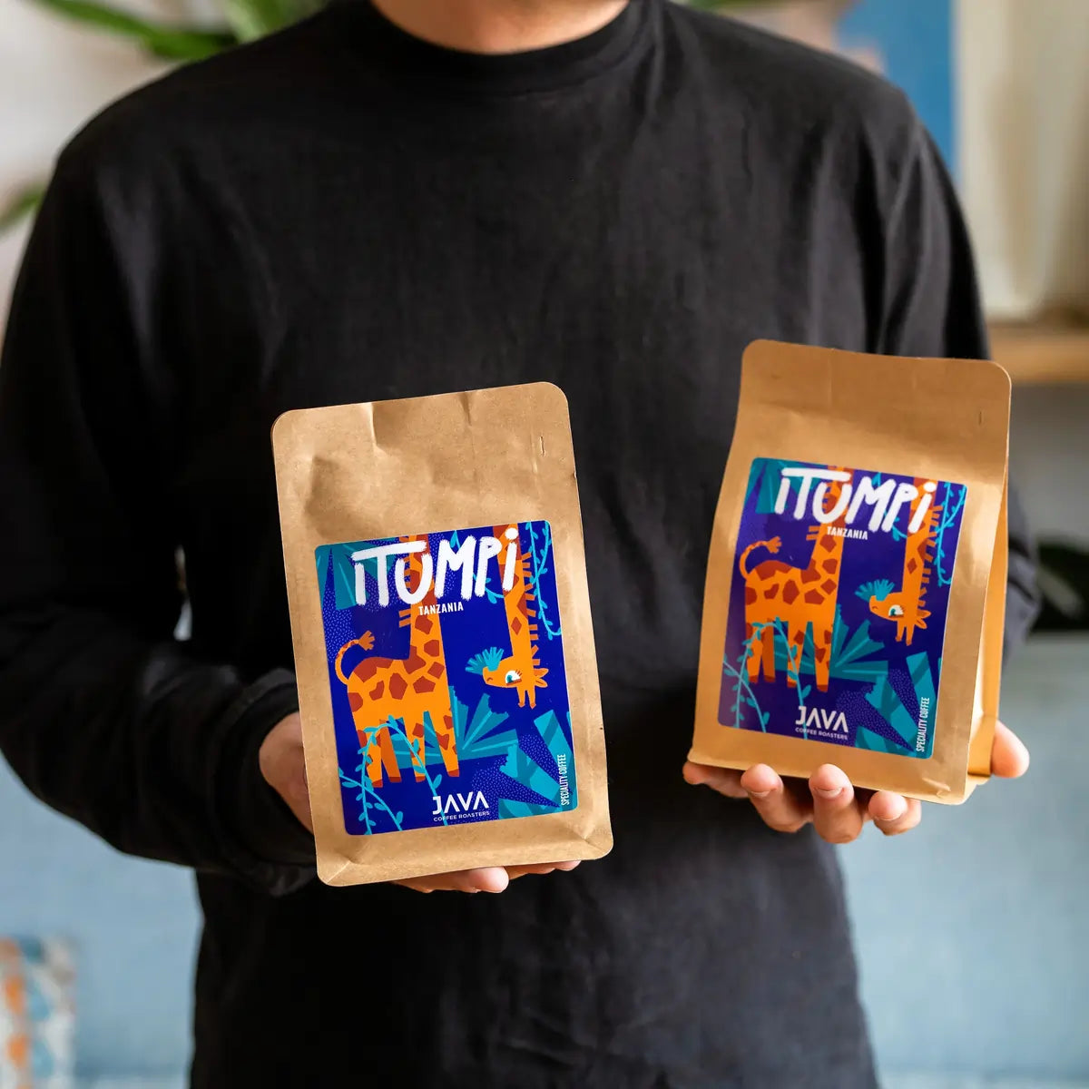 Dwie paczki kawy specialty Tanzania Itumpi od Java Coffee Roasters prezentowane w dłoniach