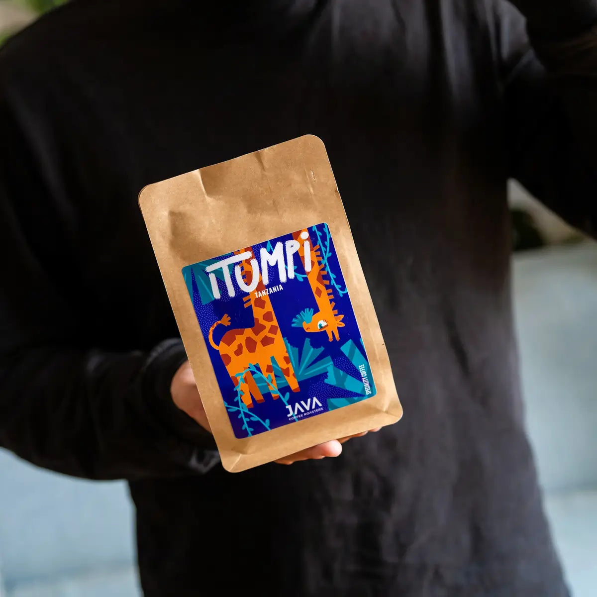 Dwie paczki kawy specialty Tanzania Itumpi od Java Coffee Roasters prezentowane w dłoniach