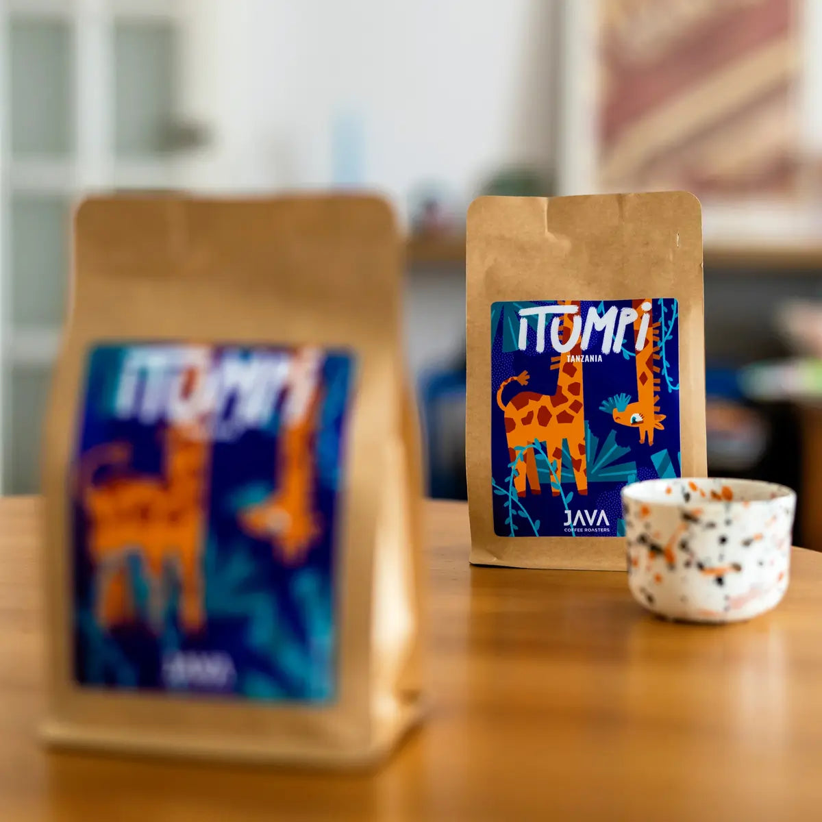 Kawa specialty Java Coffee Roasters Tanzania Itumpi w opakowaniu na drewnianym stole z filiżanką – lifestyle