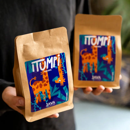 Opakowanie kawy specialty Tanzania Itumpi od Java Coffee Roasters trzymane w dłoniach na tle palarni