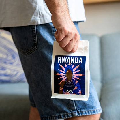 Osoba trzyma opakowanie kawy specialty Rwanda Cocatu od JAVA Coffee Roasters. Zdjęcie prezentuje produkt w naturalnym użyciu, eksponując opakowanie, autorską etykietę i charakter kawy specialty przeznaczonej do metod przelewowych.
