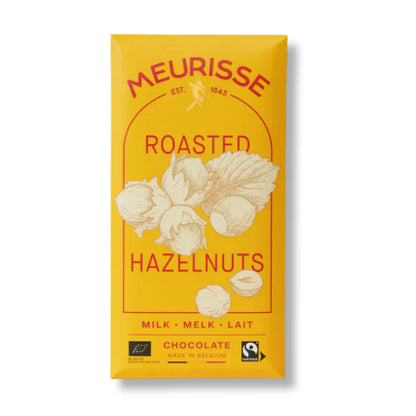 Opakowanie mlecznej czekolady Meurisse Roasted Hazelnuts 39% kakao w żółtym kolorze z ilustracją prażonych orzechów laskowych i oznaczeniami Fairtrade oraz BIO.