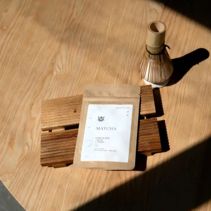 Oromatcha Matcha Noburu – opakowanie matchy i bambusowa miotełka chasen na drewnianym stole