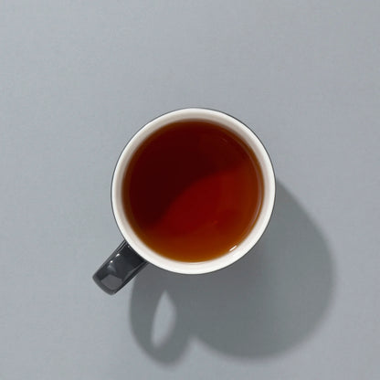 Filiżanka czarnej herbaty Suki Tea – napar widok z góry na szarym tle