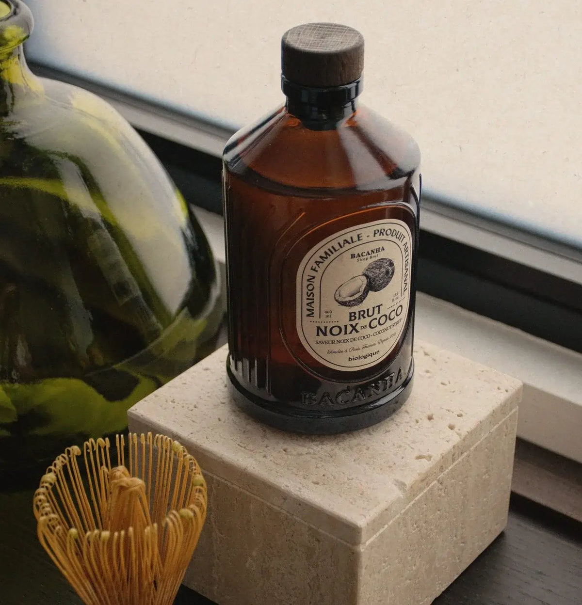 Syrop Bacanha o smaku kokosa 400 ml – organiczny syrop kokosowy w szklanej butelce, ustawiony obok narzędzi do parzenia matchy