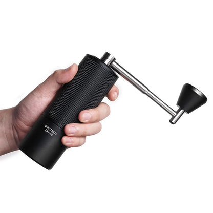 Alt: Czarny ręczny młynek do kawy Timemore Chestnut C3S Pro trzymany w dłoni – widoczna tekstura korpusu i metalowa korbka z ergonomicznym uchwytem.